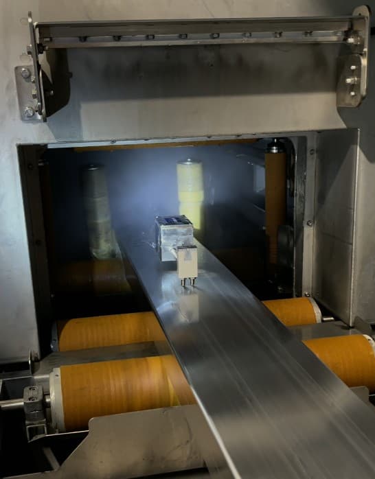 Aluminium profile entering an Extrutec EAGLE cooling-rate measurement station on orange rollers.