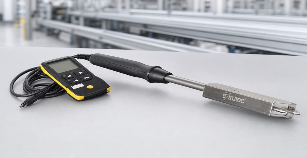 Extrutec handheld pyrometer with display unit and probe on a factory floor.
