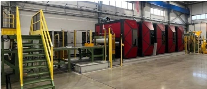 Santioli surface finishing line with red machine housings and yellow access stairs in a factory hall.